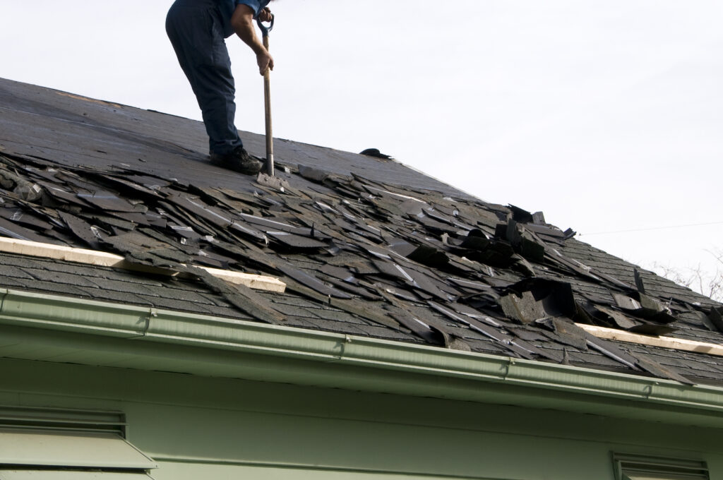Damaged roof with shingles coming off of it.